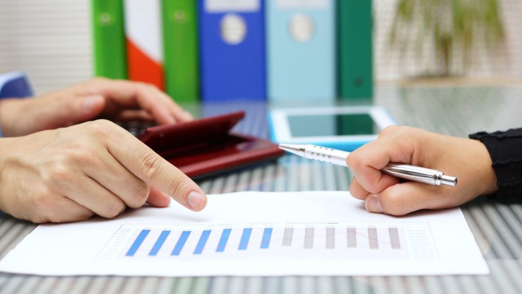 printed bar graph with a male hand and female  hand