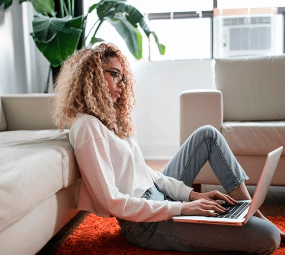 A woman sitting on the floor with a laptop, keywords her work for International SEO.