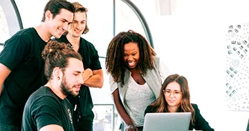 A group of people in an office, looking at a laptop for international marketing strategies.